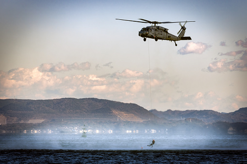 Yokosuka, Kanagawa / Japan - December 17, 2020:  A US Navy MH-60 helicopter hovers while rescue swimmers train in Tokyo Bay.