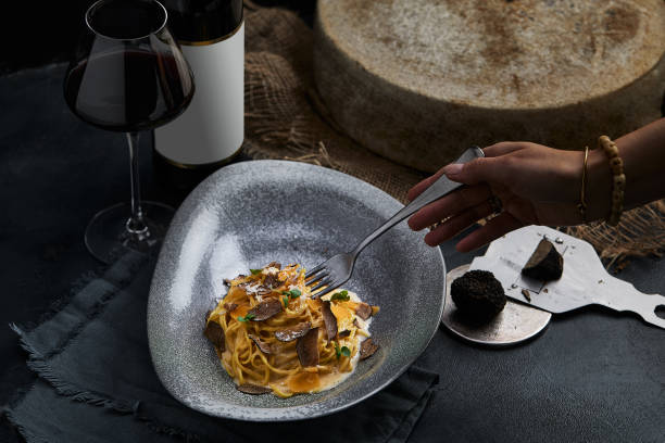 Italian cuisine - spaghetti with black truffle on a gray plate and bottle of wine. Selective focus. Vertical Italian cuisine - spaghetti with black truffle on a gray plate and bottle of wine. Selective focus. Vertical chocolate truffle stock pictures, royalty-free photos & images