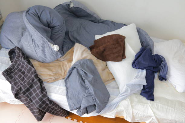 istock Beds, duvets and pillows in a dirty room with messy clothes 1293680524