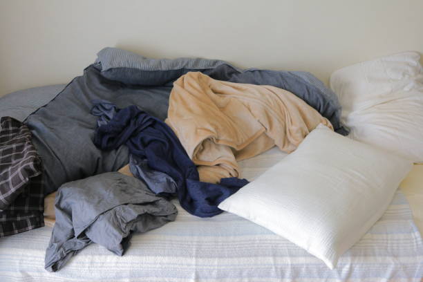 istock Beds, duvets and pillows in a dirty room with messy clothes 1293681149