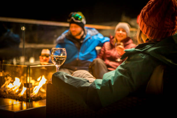 friends sitting by fire at ski apres at night. - apres ski fotos imagens e fotografias de stock