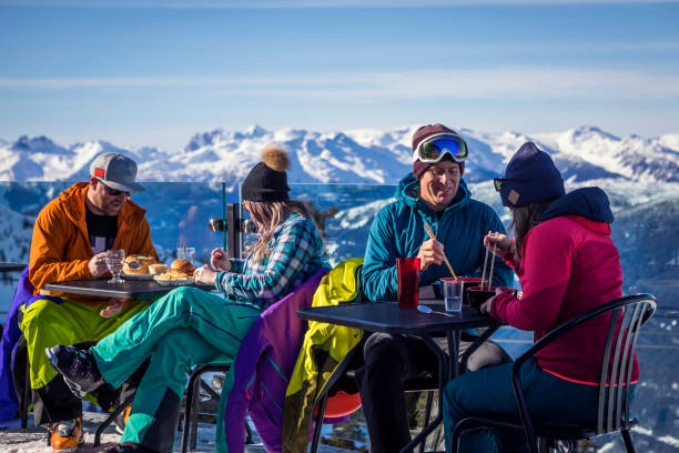 Group of friends enjoying apres-ski at top of Whistler mountain. Skiers having drinks at the top during their ski  vacation in Whistler, Canada. apres ski stock pictures, royalty-free photos & images