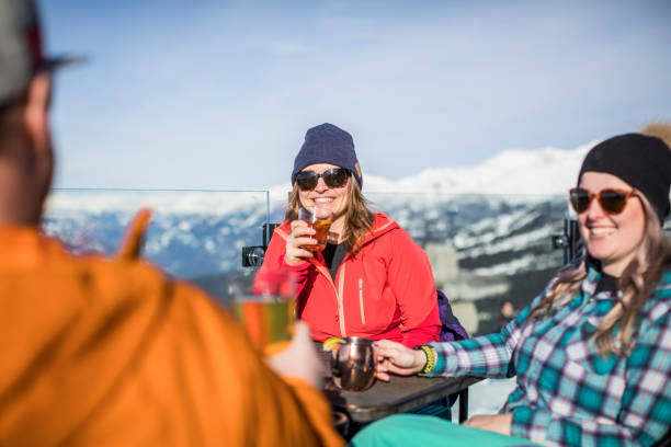 Group of friends enjoying apres-ski at top of Whistler mountain. Skiers having drinks at the top during their ski  vacation in Whistler, Canada. apres ski stock pictures, royalty-free photos & images