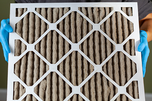 someone holding a very dirty clogged air conditioner furnace filter