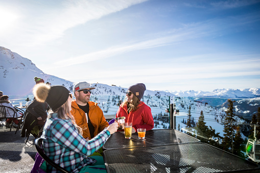 Group of friends enjoying apres-ski at top of Whistler mountain.