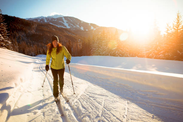 Alone woman cross country skiing at sunset in ski resort. Cross country skiing in Whistler valley. whistler mountain stock pictures, royalty-free photos & images