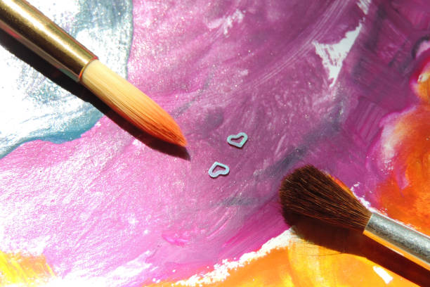 istock two paint brushes and two decorative hearts on a color abstract stain background 1293689369