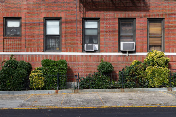 istock Empty Sidewalk next to an Old Brick Apartment Building with Window Air Conditioners in Astoria Queens New York 1293694730