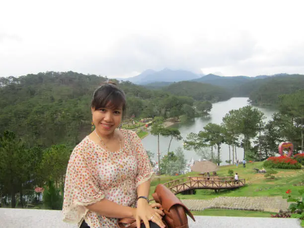 Photo of A beautiful woman sit on the top of mountain with nice landscape behind her