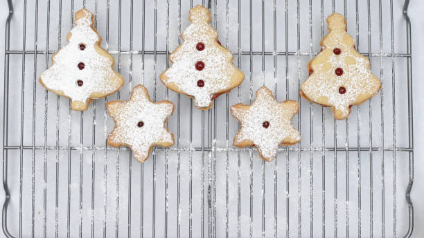istock Baked Christmas cookies with raspberry jam and powdered sugar topping close up on cooling rack directly from above 1293707764
