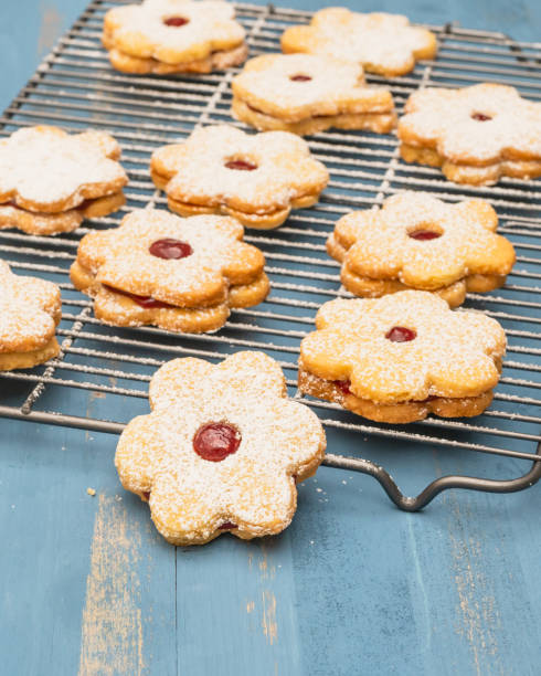 istock Flower shaped shortbread cookies filled with raspberry jam close up on blue wooden background 1293708310