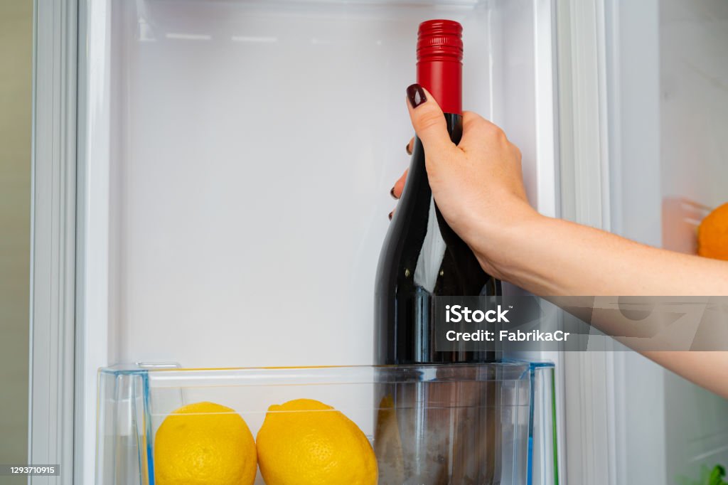 冷蔵庫からワインのボトルを取る女性の手 - カラー画像のロイヤリティフリーストックフォト