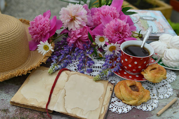 istock Still life with open diary book, bunch of flowers, cup and hat on the table. 1293719231