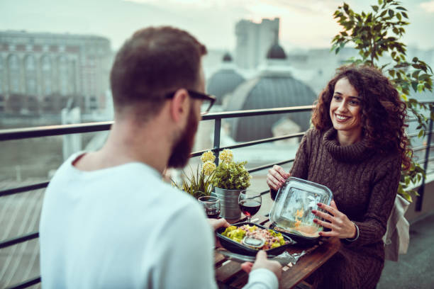 Couple Enjoying Date On Rooftop And Eating Salad With Wine Together Couple Enjoying Date On Rooftop And Eating Salad With Wine Together caesar salad food salad tuna stock pictures, royalty-free photos & images