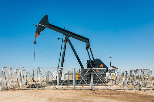 Oil Pumpjack - Oil Well Pump - in Bahrain Middle Eastern Desert Oil Field under blue summer sky. Oil Industry in the Arabian Persian Gulf Countries. Bahrain, Middle East, Western Asia.