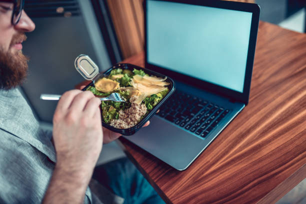 istock Modern Male Eating Takeaway Salad While Working On Laptop 1293721074
