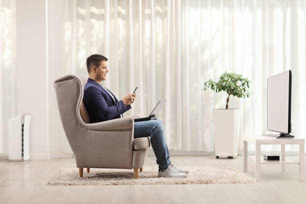 istock Man in an armchair with a laptop computer and a mobile phone 1293722122