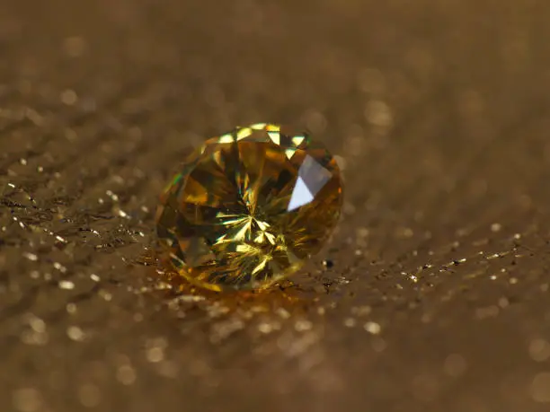 Close up picture of yellow colored diamond gems on golden background