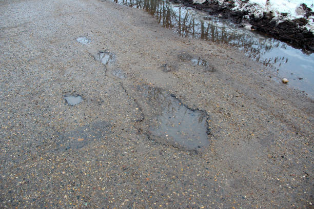 田舎に穴がある古い悪いアスファルト道路 - pot hole ストックフォトと画像