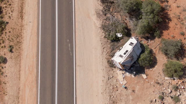 Aerial of camper caravan crashed on a highway accident in a desert rural area. Motorhome crashing event on the motorway. Travel and insurance concepts