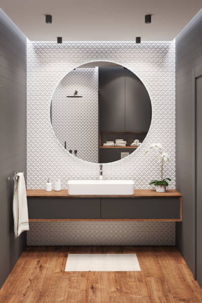 czarno-biała łazienka z dużym okrągłym lustrem na białej ścianie mozaiki, umywalka na drewnianej szafce, orchidea, ręcznik, dywan na drewnianej podłodze. - loft apartment bathroom mosaic tile zdjęcia i obrazy z banku zdjęć