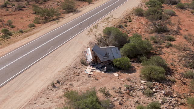 Aerial of camper caravan crashed on a highway accident in a desert rural area. Motorhome crashing event on the motorway. Travel and insurance concepts