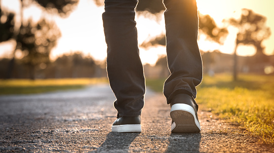 Man walking outdoors in the park at sunset. Closeup on shoe. Concept of new start and freedom. High quality photo