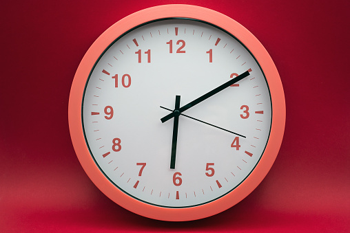 Closeup of modern analog clock on red background