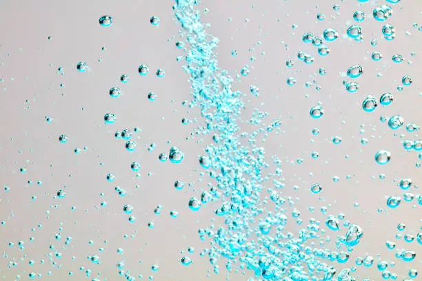 Close-up of air bubbles under water against bright background.
