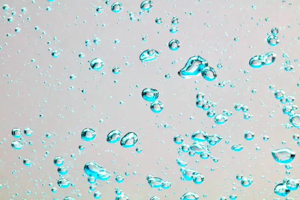 Close-up of air bubbles under water against bright background.