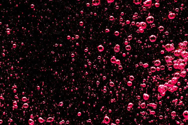 Close-up of air bubbles under water against black background.