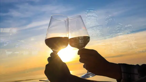 Photo of Selective focus of couple hands which  Couple drinking wine on the rooftop bar restaurant and the city background