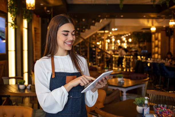 istock Portrait of friendly waitress holding a tablet computer looking at the camera smiling 1293735252