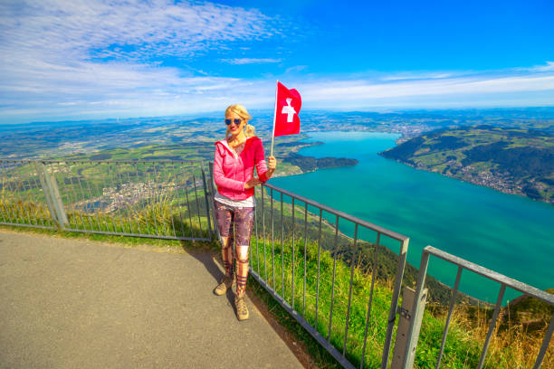 Woman with Swiss flag looking alpine panorama from Rigi-Kulm summit of Mount Rigi. Tourism in Canton of Lucerne, Central Switzerland. Amazing views and scenic landscape of popular tourist attraction.