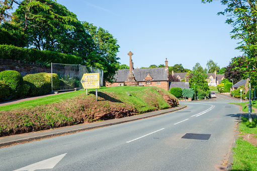 Caldy, UK: Jun 23, 2020: A general view of the junction where the A5141 seamlessly becomes the A5140 in the Wirral village of Caldy. An old road direction sign is visible on the left.