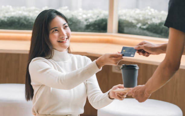Woman paying coffee by credit card Asian beautiful woman smiling and paying for coffee by credit card. Lifestyle and Finance Concept. asian cashier stock pictures, royalty-free photos & images
