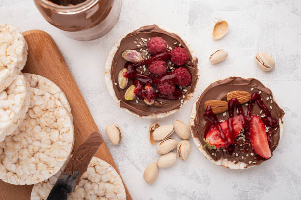 istock Rice cakes with chocolate-nut paste spread and berries and nuts top view 1293746946