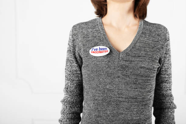 istock Middle age caucasian female in sweater with  button pin I've been vaccinated stands on white wall background 1293751611