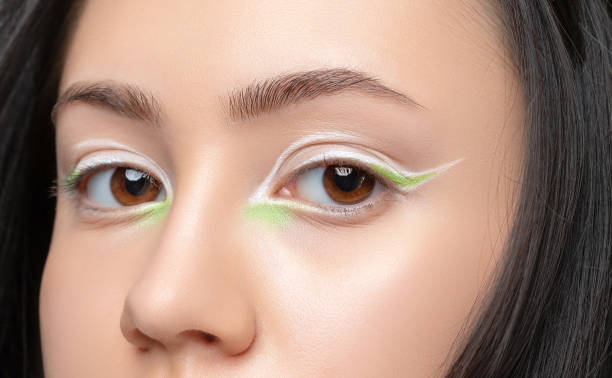 Portrait of a beautiful teenage girl with dark hair, with beautiful creative white and green makeup and healthy clean skin.  Makeup and cosmetology concept. Portrait of a beautiful teenage girl with dark hair, with beautiful creative white and green makeup and healthy clean skin.  Makeup and cosmetology concept. eyeliner stock pictures, royalty-free photos & images