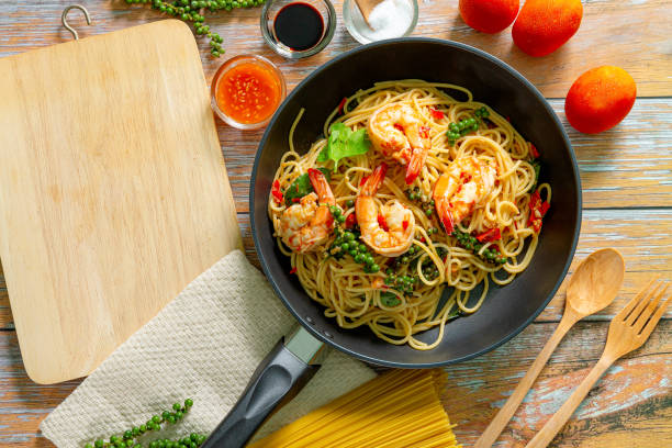 istock Spaghetti with prawns and vegetables on wooden background 1293757587