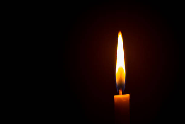 istock Close up single candle light and flame on black background 1293757788