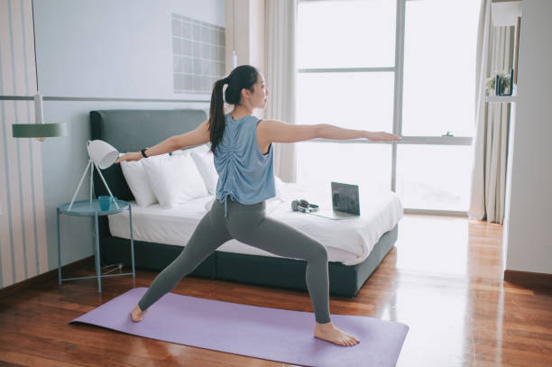 istock An asian chinese young woman practicing yoga exercising at home bedroom e learning using laptop online class 1293758786