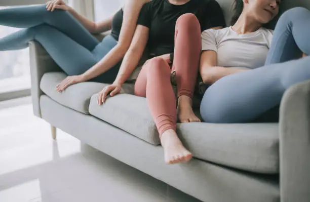 Photo of asian chinese group of female with yoga clothing sitting on sofa posing in living room