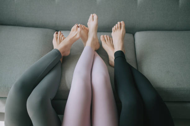 gambe asiatiche cinesi con pantaloni da yoga appoggiati su gambe divano incrociate - fuseaux foto e immagini stock