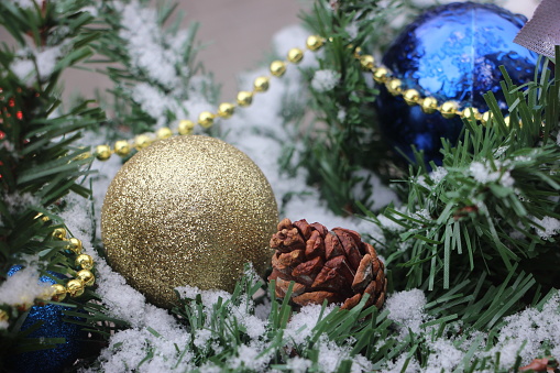 Christmas decorations on the branches of fir. Glittering golden and blue Christmas baubles.