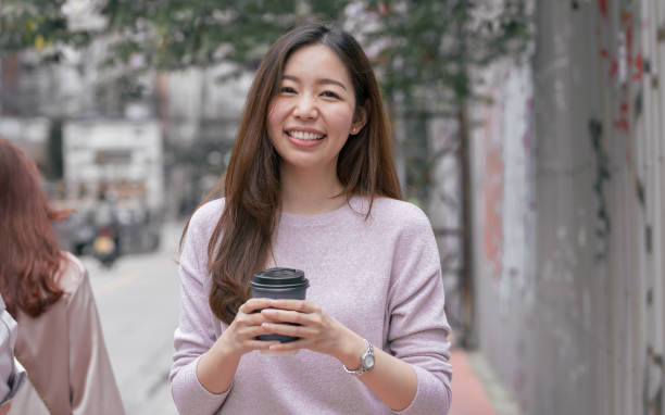 istock Woman drinking coffee while walking beside street 1293761605