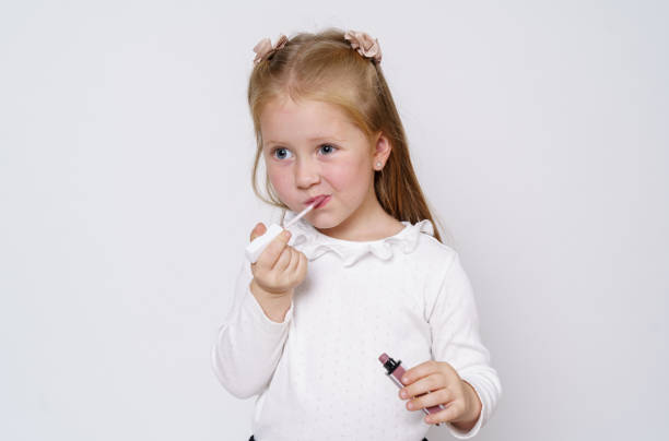 istock The girl paints her lips with lipstick. Isolated over white background. 1293765166