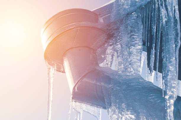 istock icicle cleaning from rooftop outdoors at sunny day. roof icicle problem concept 1293765357