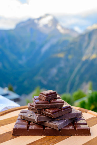 istock Handmade pure dark swiss chocolate and Alpine mountains on background 1293766435