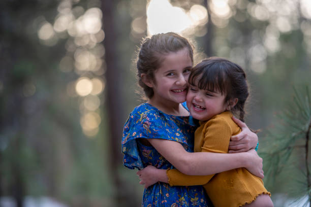 A pair of siblings hugs each other as they spend time together outdoors.